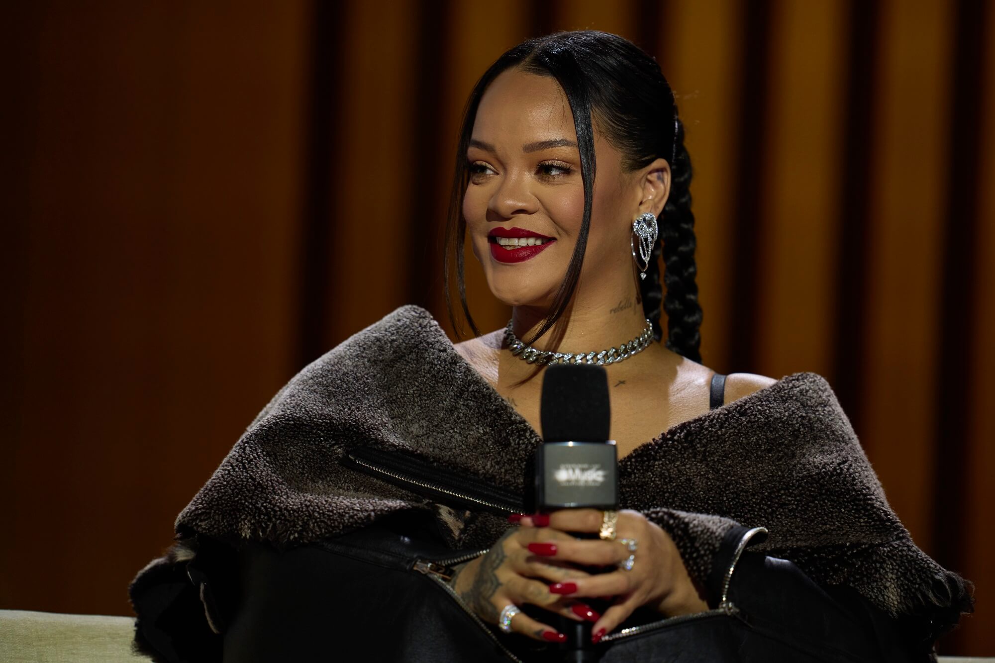 Rihanna smiles while holding a microphone