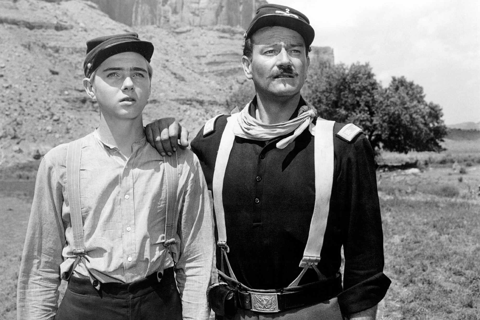'Rio Grande' Claude Jarman Jr. as Trooper Jefferson 'Jeff' Yorke and John Wayne as Lt. Col. Kirby Yorke looking ahead in the desert. Wayne has his hand resting on Jarman Jr.'s shoulder.