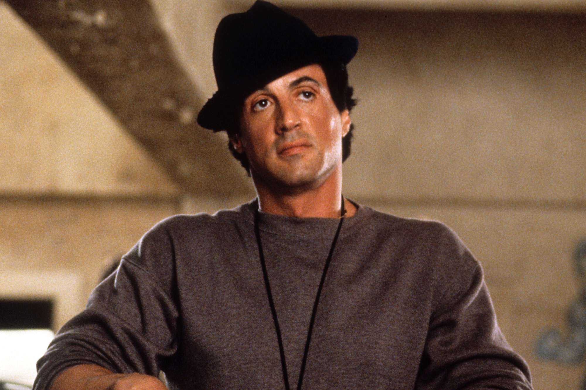 'Rocky V' movies - Sylvester Stallone as Rocky wearing a sweater and hat, with his arms resting over the side of the boxing ring.