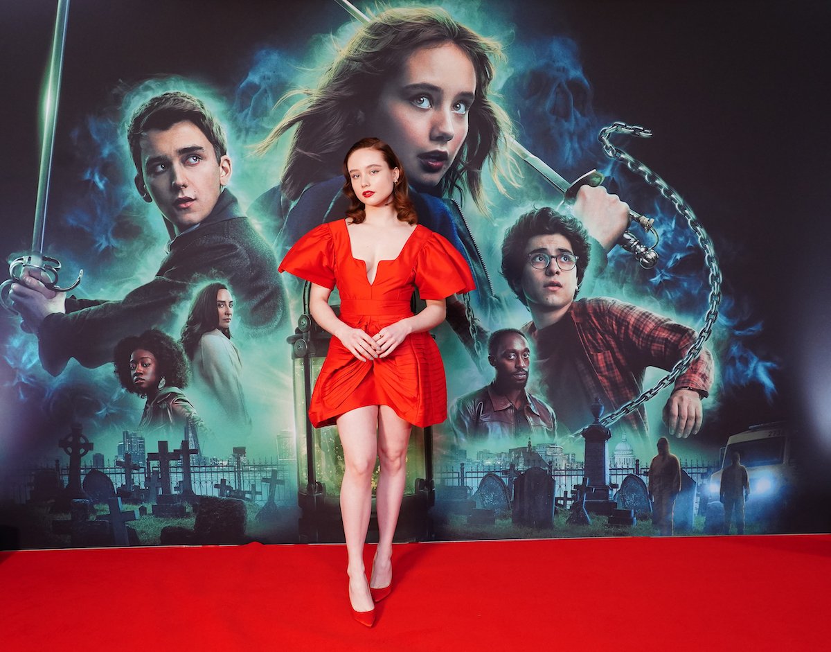 Ruby Stokes poses in front of a "Lockwood & Co." poster at a premiere screening.