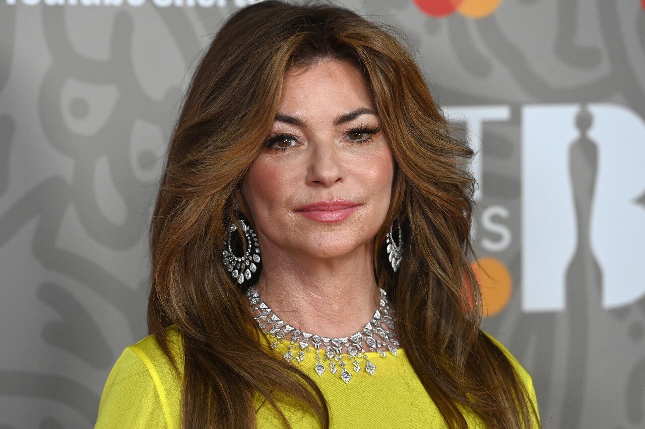 Shania Twain wears a yellow top and silver jewelry.