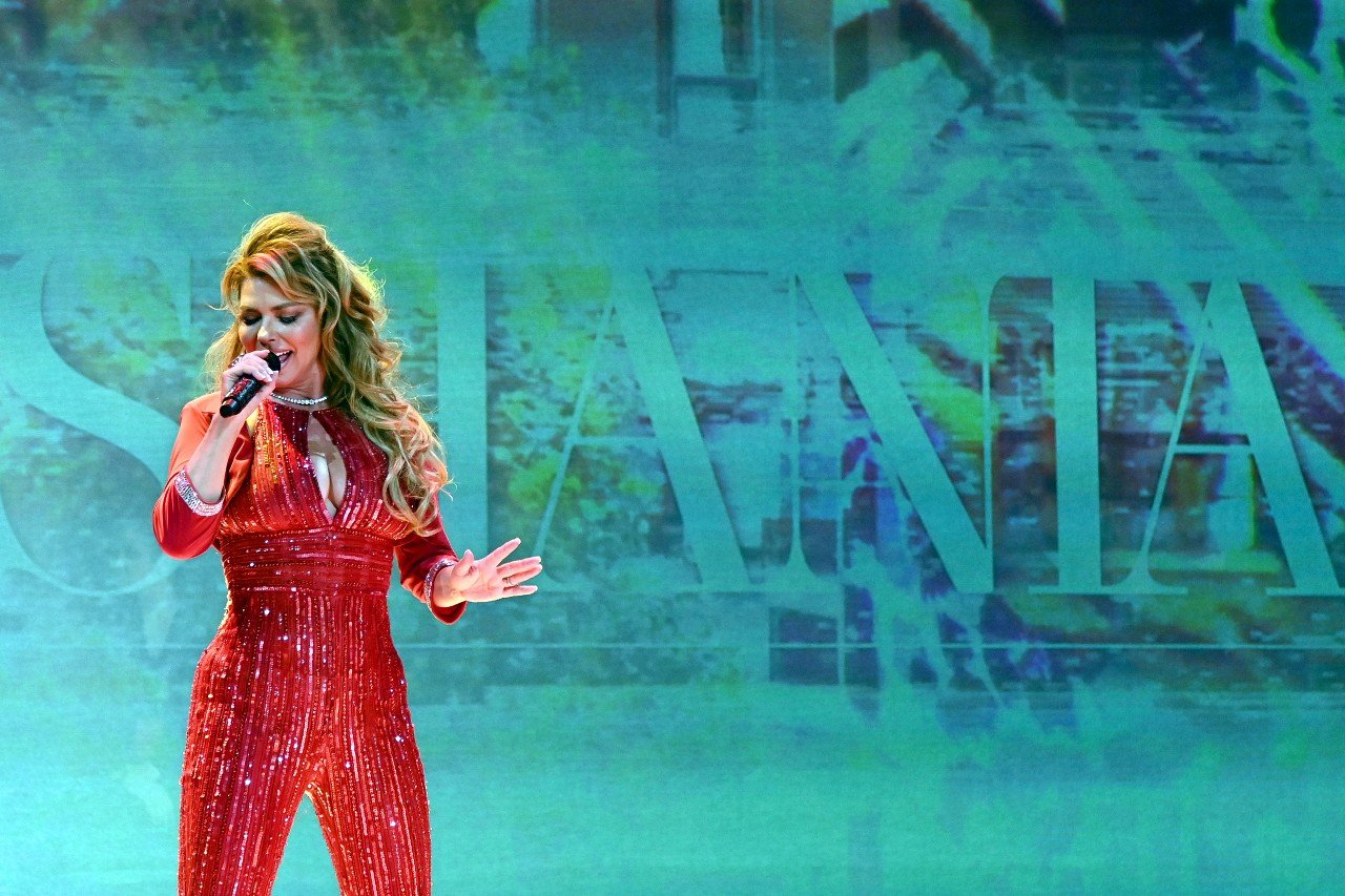 Shania Twain sings while wearing a red outfit. 