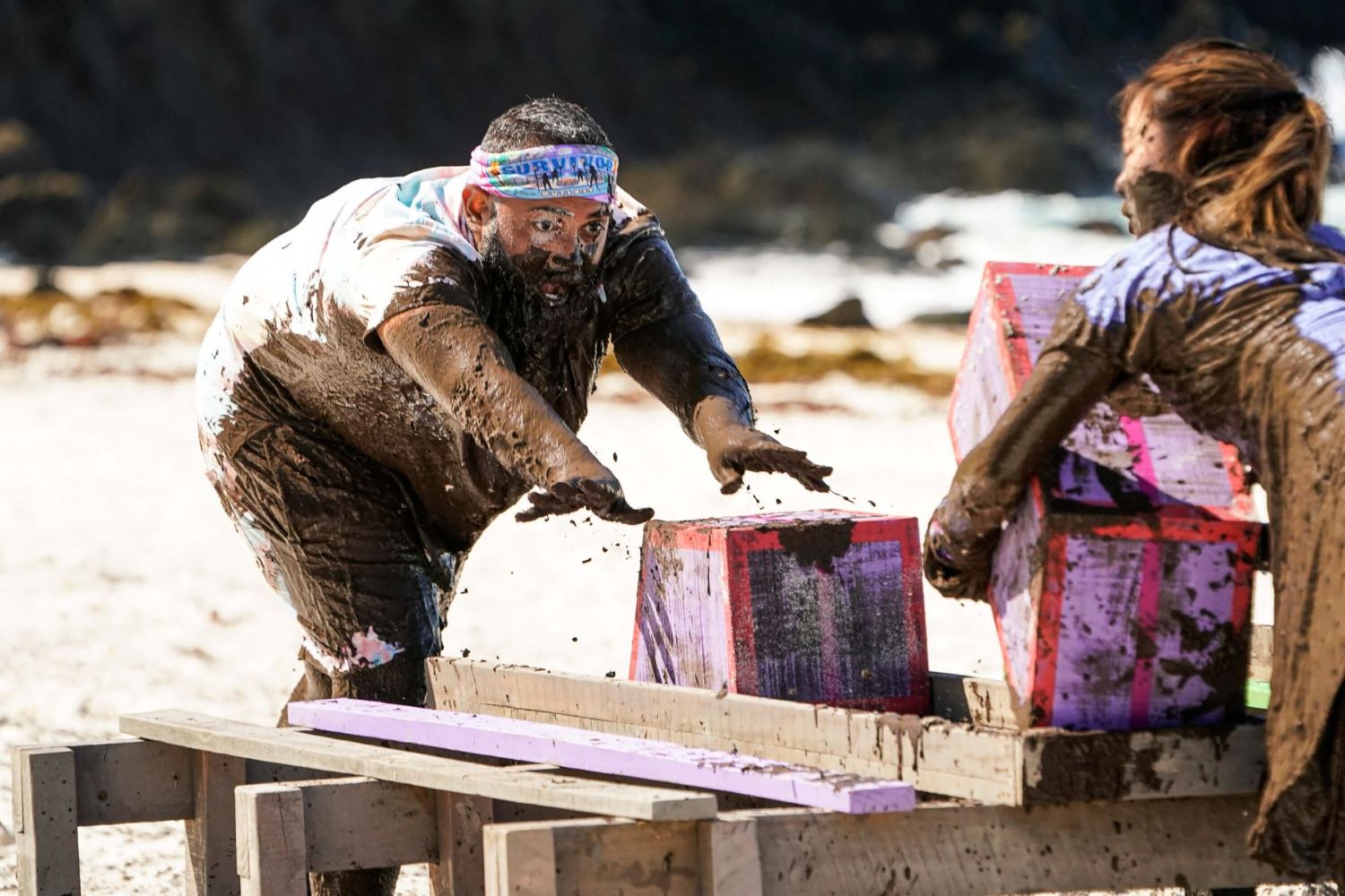 Yamil "Yam Yam" Arocho gets muddy during a challenge in the 'Survivor 44' premiere, which, according to spoilers, features a medical evacuation. Yam Yam's clothes are covered in mud and he wears his purple 'Survivor' buff around his head.