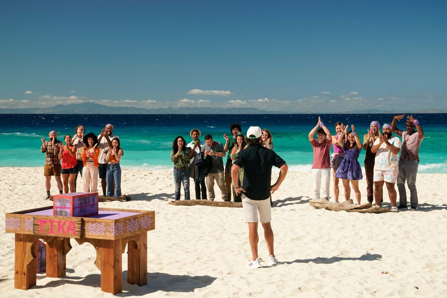 Host Jeff Probst welcomes the 'Survivor' Season 44 cast during the premiere. The three tribes — Ratu, Soka, and Tika —stand on their designated mats on the beach as they await their first challenge. Probst wears a black button-up shirt with rolled-up sleeves, white shorts, white gym shoes, and a white 'Survivor' baseball cap.