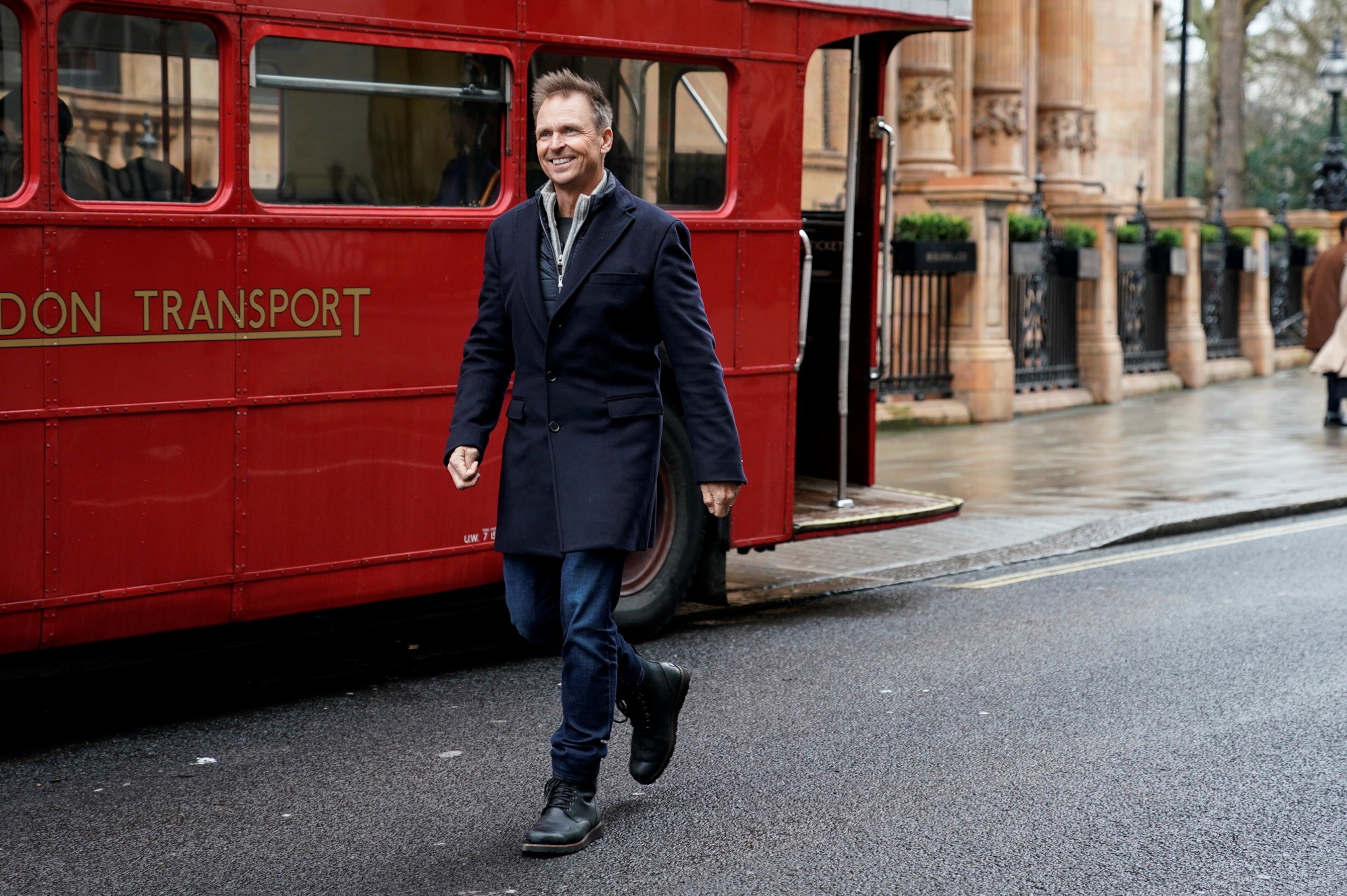 Phil Keoghan, the host of 'The Amazing Race' Season 35, wears a black coat and jeans.