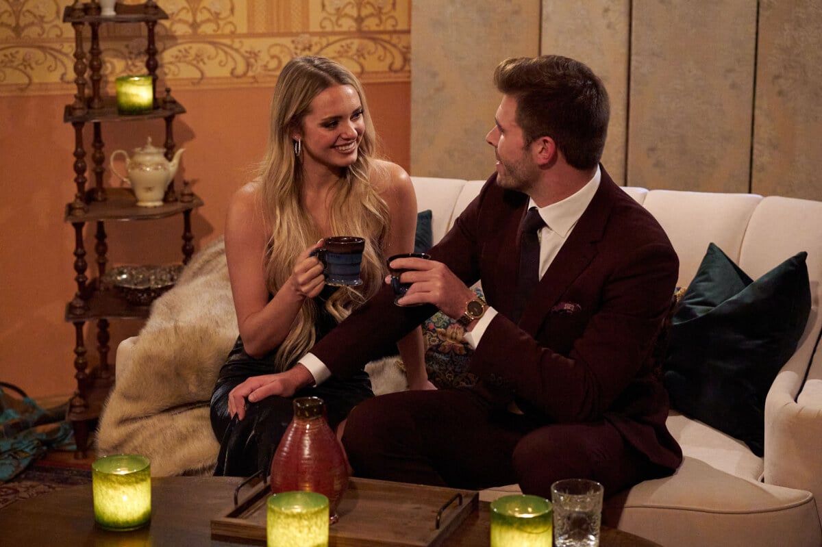 During The Bachelor 2023 Week 6, Brooklyn Willie and Zach Shallcross talk on the couch. Brooklyn holds a mug.