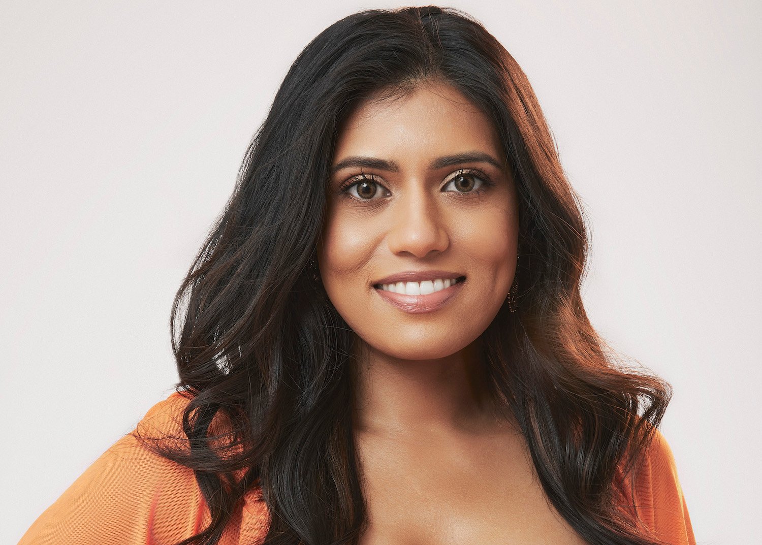 'The Bachelor' star Lekha Ravi wearing an orange dress in her official headshot for the series.