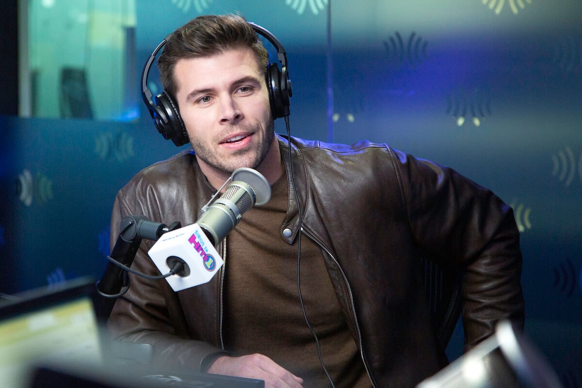 "The Bachelor" season 27 star Zach Shallcross wears headphones and speaks into a microphone while seated for an interview.