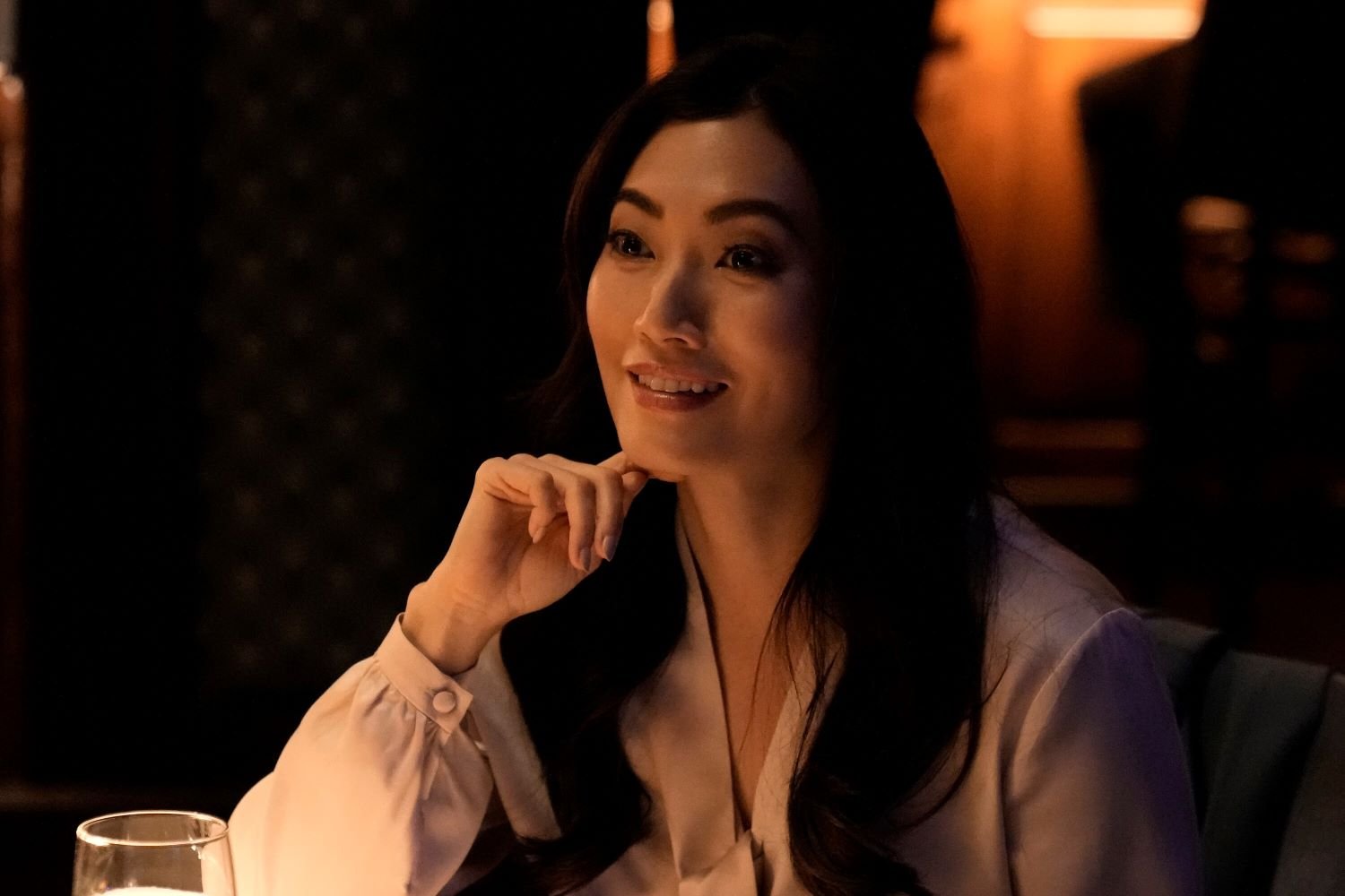 Catherine Haena Kim, in character as Emma Hill in 'The Company You Keep' Episode 2, wears a white long-sleeved blouse.