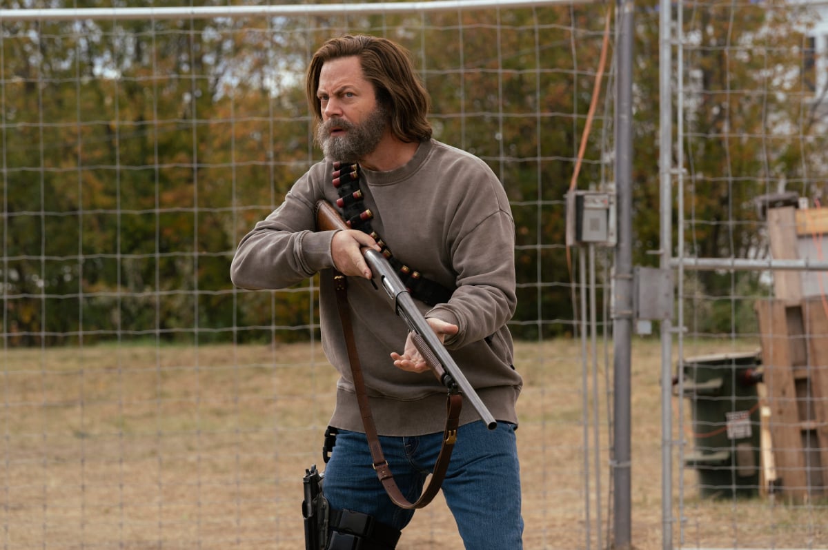 Nick Offerman as Bill in The Last of Us holds a shotgun outside his electric fence.