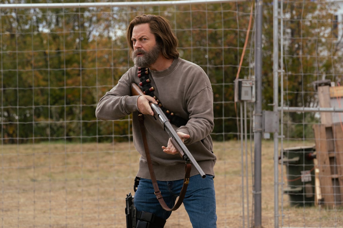 Nick Offerman as Bill in The Last of Us holds a shotgun outside his electric fence. 