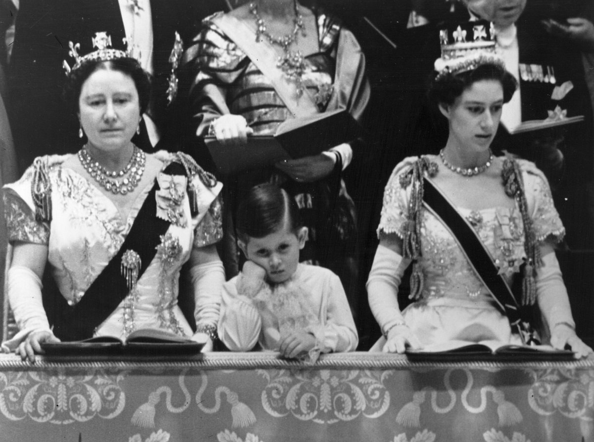 The Queen Mother and then-Prince Charles with Princess Margaret standing in the royal box at Westminster Abbey watching the Coronation ceremony of Queen Elizabeth II
