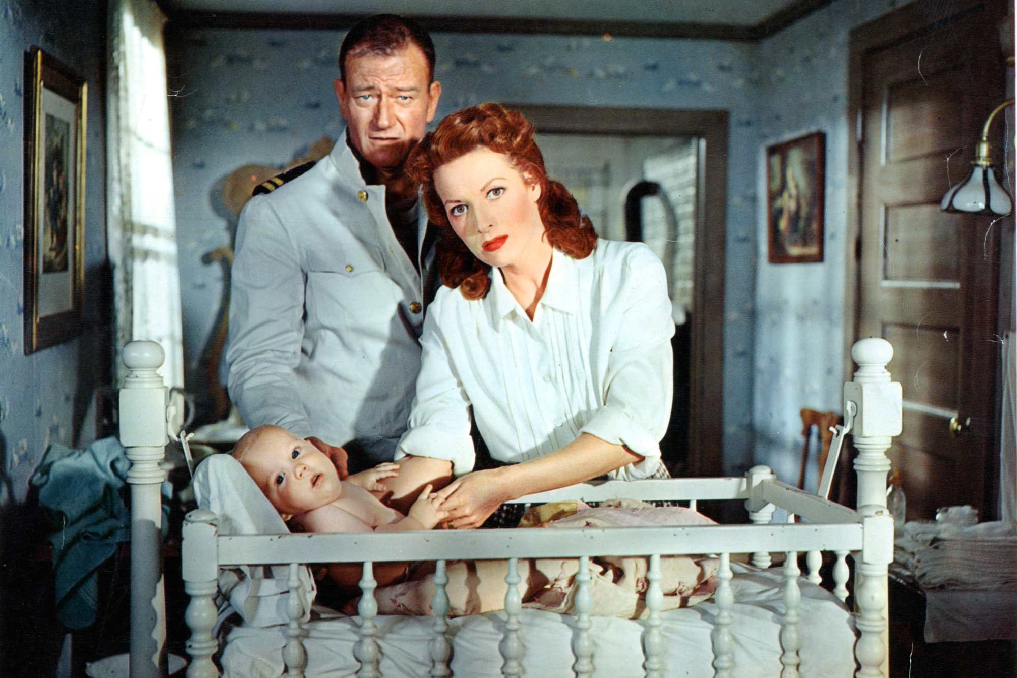 'The Wings of Eagles' John Wayne as Frank W. 'Spig' Wead and Maureen O'Hara as Min Wead standing over a baby in their crib.