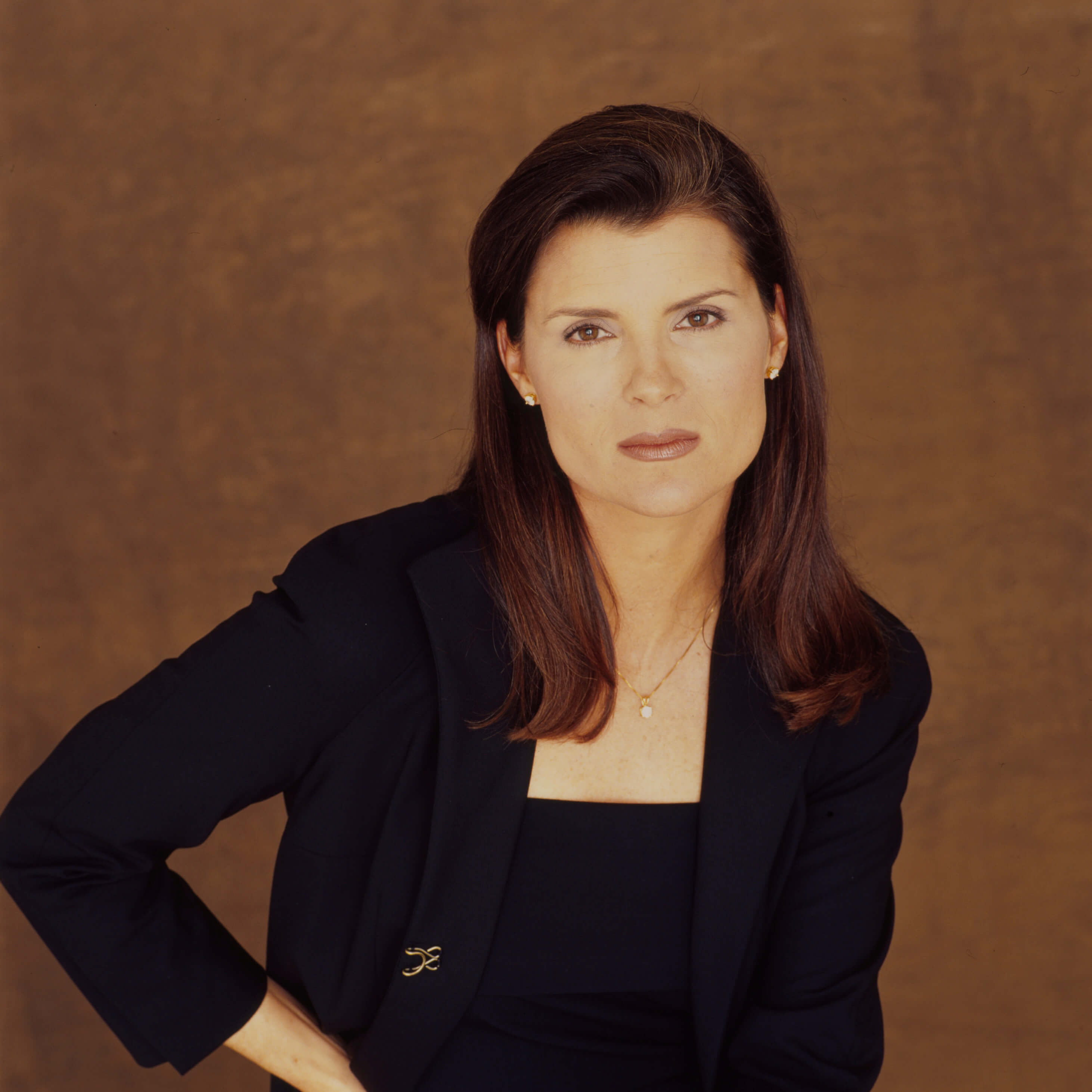 'The Young and the Restless' star Kimberlin Brown dressed in a blue suit; posing in front of a brown backdrop.