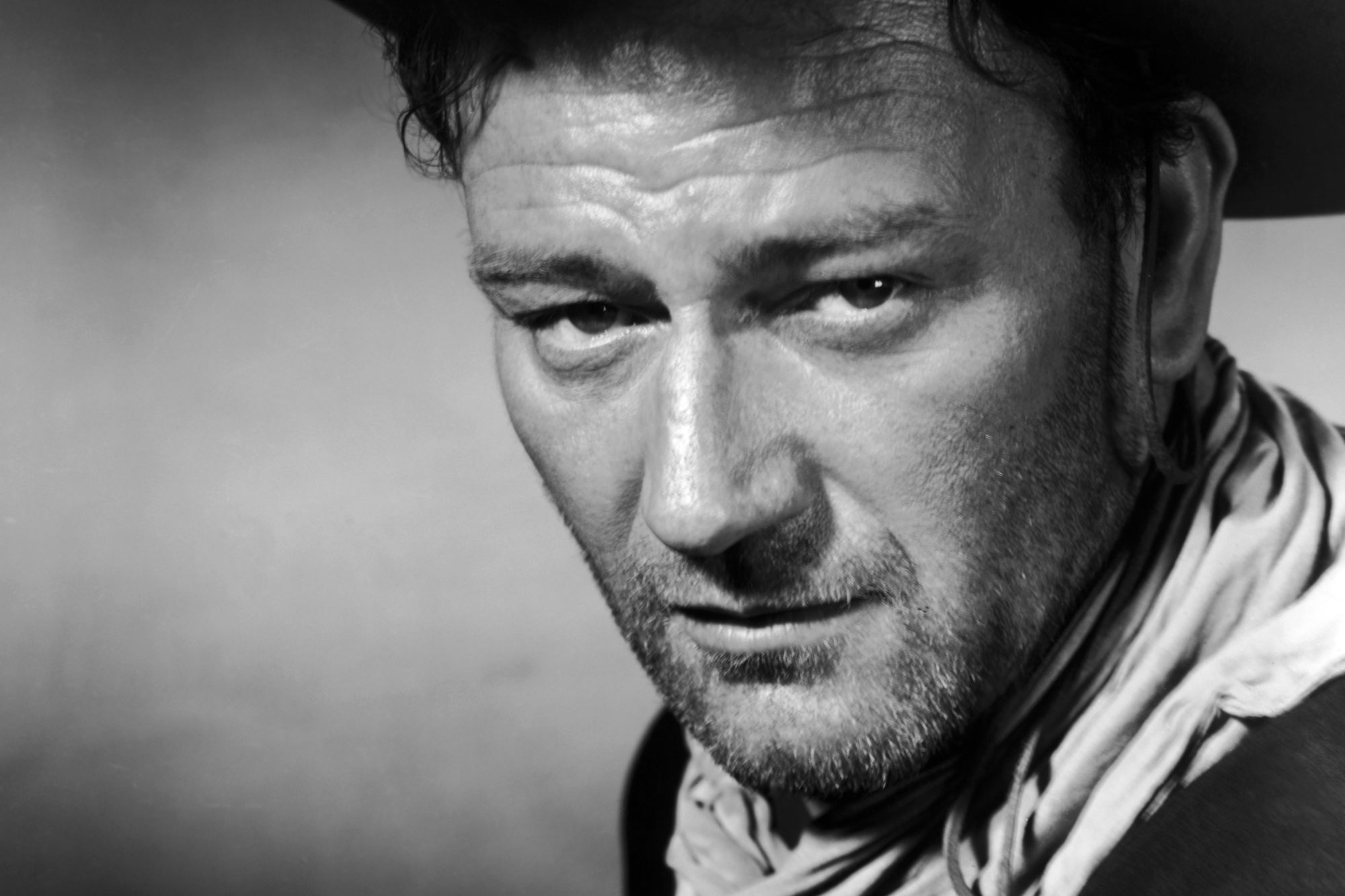 'Three Godfathers' John Wayne as Robert Hightower in a black-and-white picture giving a serious look into the camera wearing a Western costume