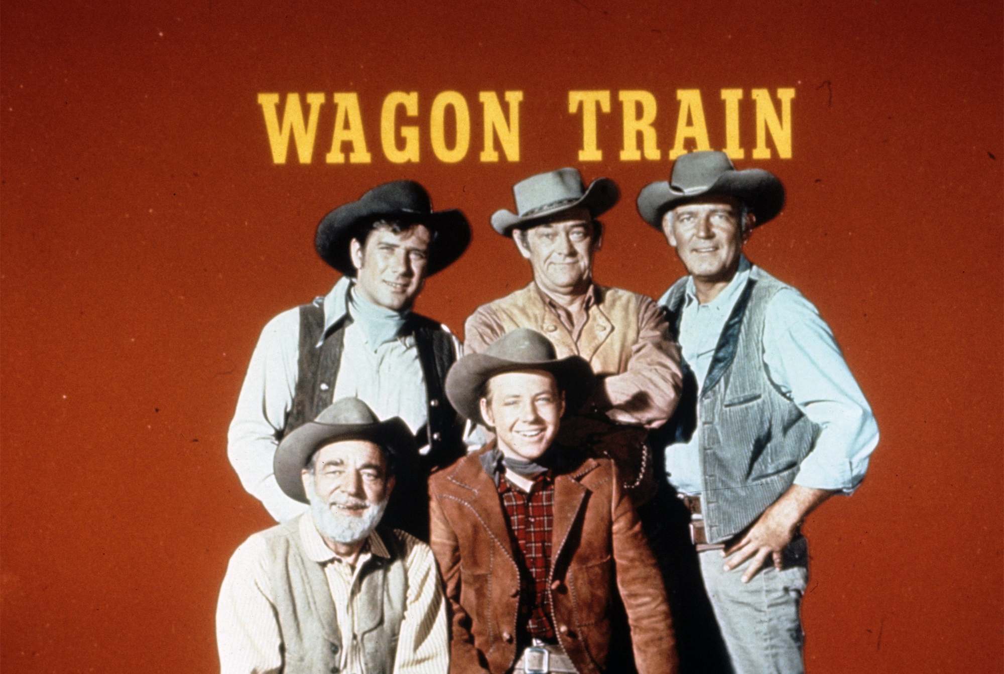 'Wagon Train' Top: Robert Fuller, John McIntyre, Terry Wilson. Seated: Frank McGrath, Michael Burns smiling in front of title logo with a red background.