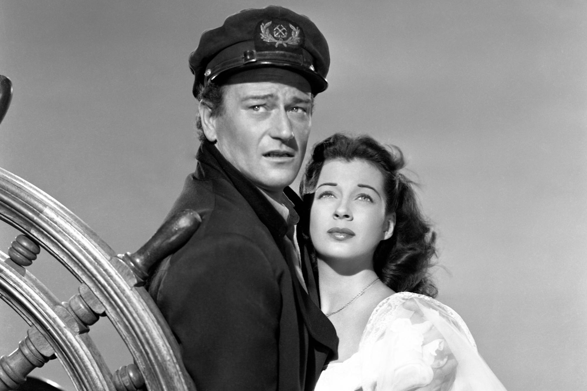 'Wake of the Red Witch' John Wayne as Captain Ralls and Gail Russell as Angelique Desaix looking surprised behind a ship's wheel