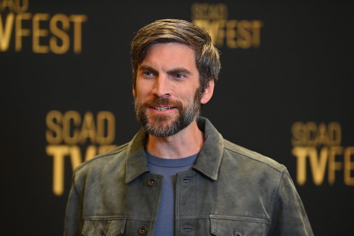 Wes Bentley stands in front of a black backdrop with the SCAD TV logo on it.