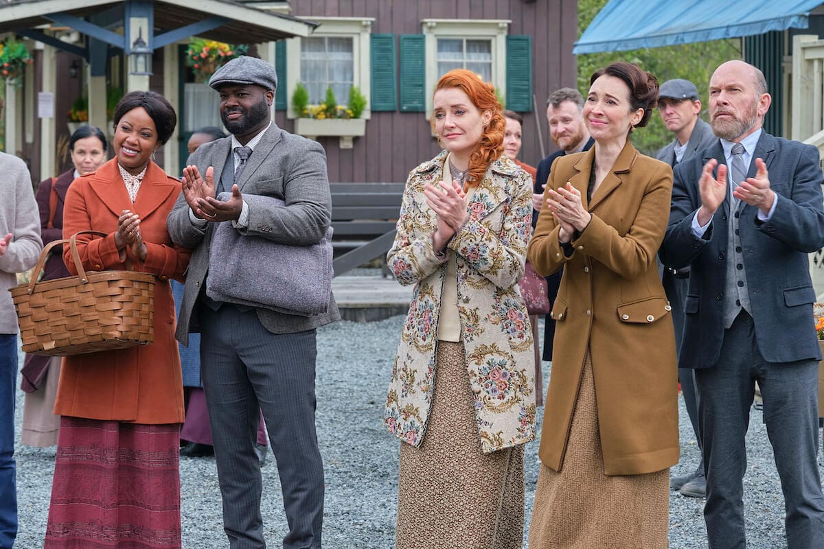 Group of 'When Calls the Heart' characters standing in the street and clapping. Hallmark recently renewed 'When Calls the Heart' for season 11