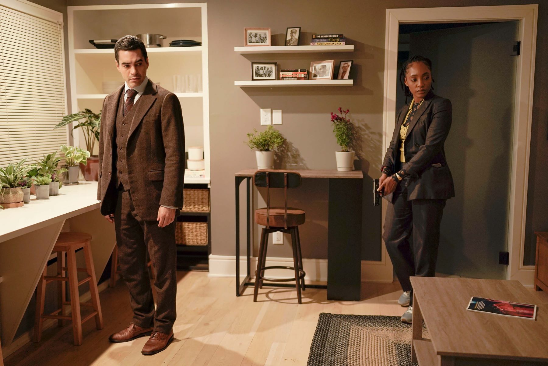 Ramón Rodríguez as Will Trent and Iantha Richardson as Faith Mitchell in 'Will Trent' Season 1 Episode 6 on ABC. Will wears a dark brown three-piece suit. Faith wears a dark gray suit over a light yellow sweater.