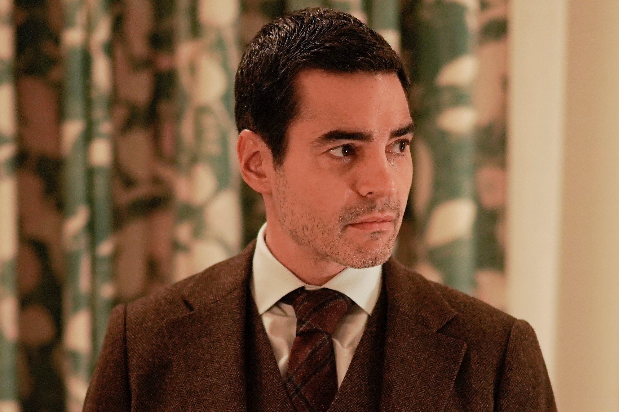 Ramón Rodríguez, in character as Will Trent in 'Will Trent' Season 1, which doesn't air a new episode tonight, Feb. 7, wears a brown three-piece suit over a white button-up shirt and dark red plaid tie.