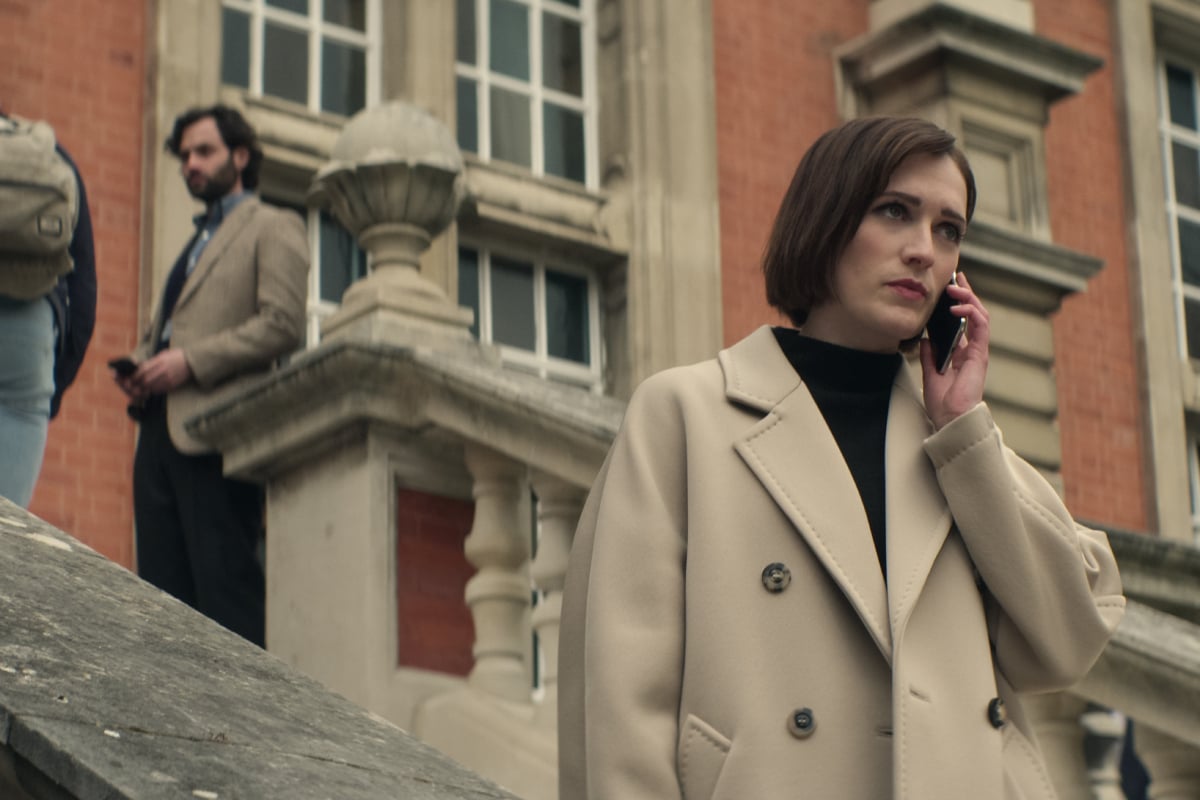 In You Season 4, Joe Goldberg stands on the stairs behind Kate, who is on the phone.