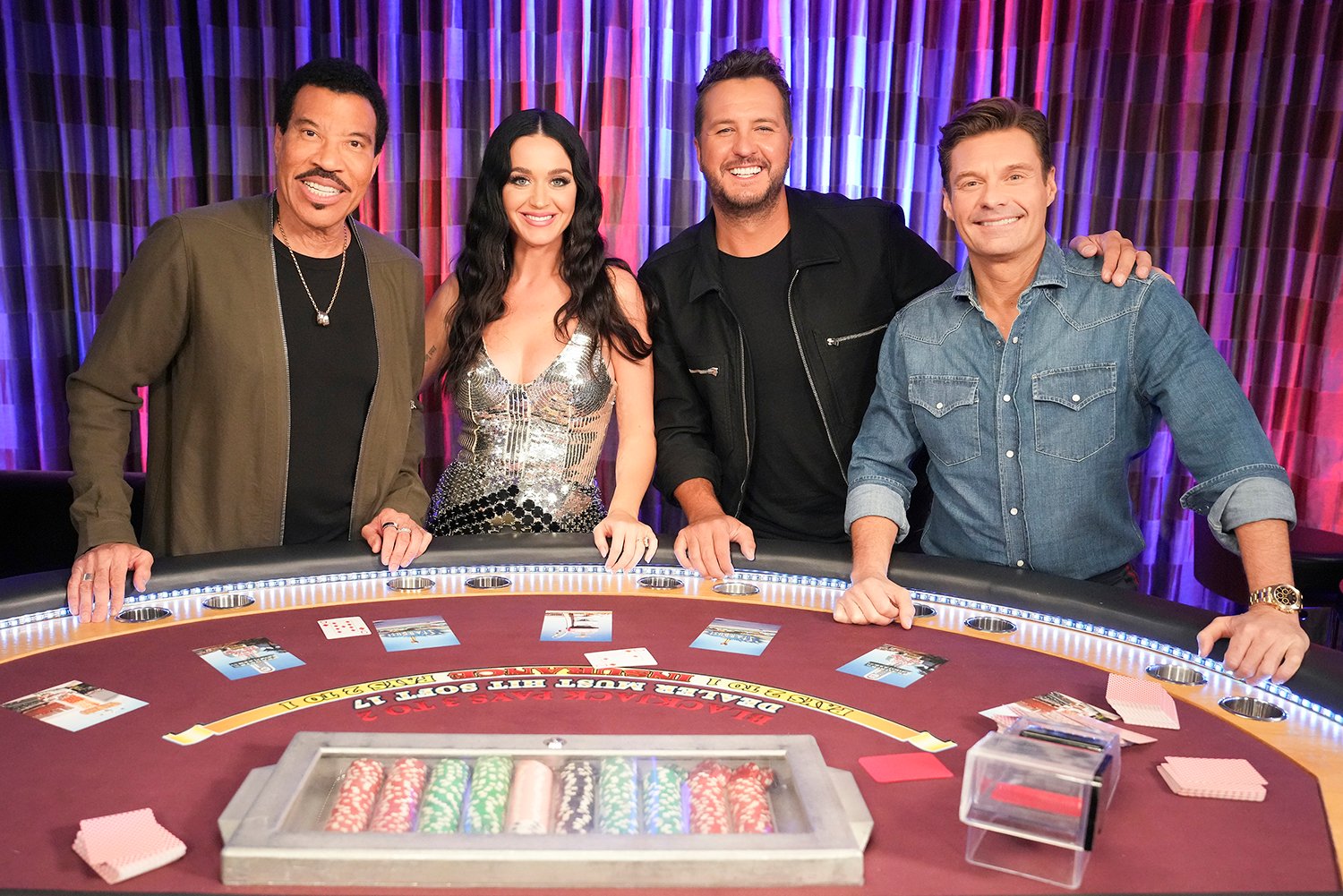 Lionel Richie, Katy Perry, Luke Bryan, and Ryan Seacrest stand around a card table in American Idol Season 21 promo image
