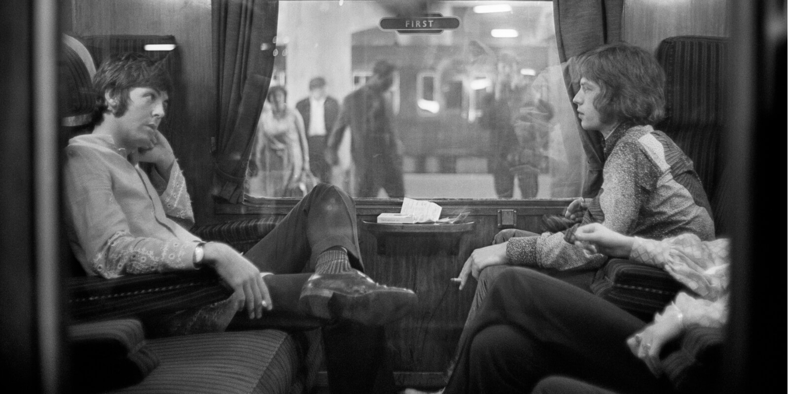 Paul McCartney and Mick Jagger ride a train together in August 1967.
