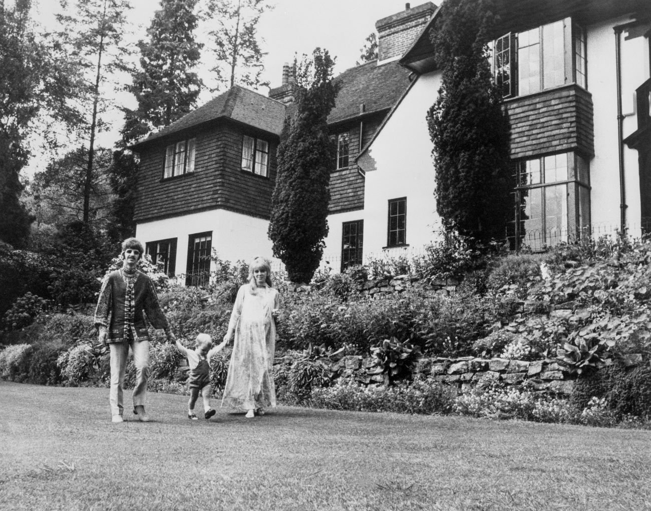 A black and white picture of Ringo Starr and Maureen Starkey holding hands with Zak Starkey.