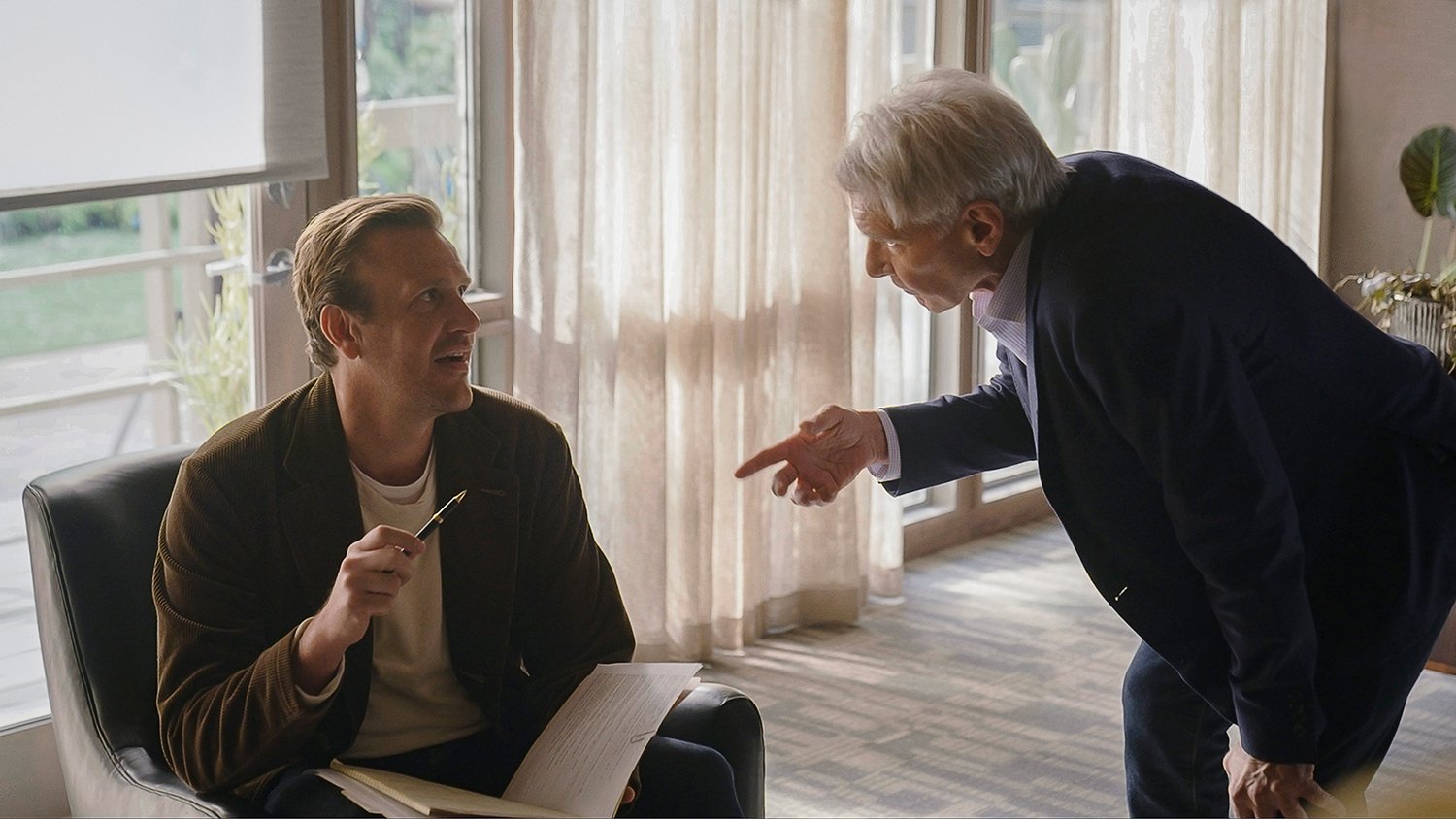 Jason Segel (as Jimmy) sitting with a book in his lap while Harrison Ford (as Paul) scolds him