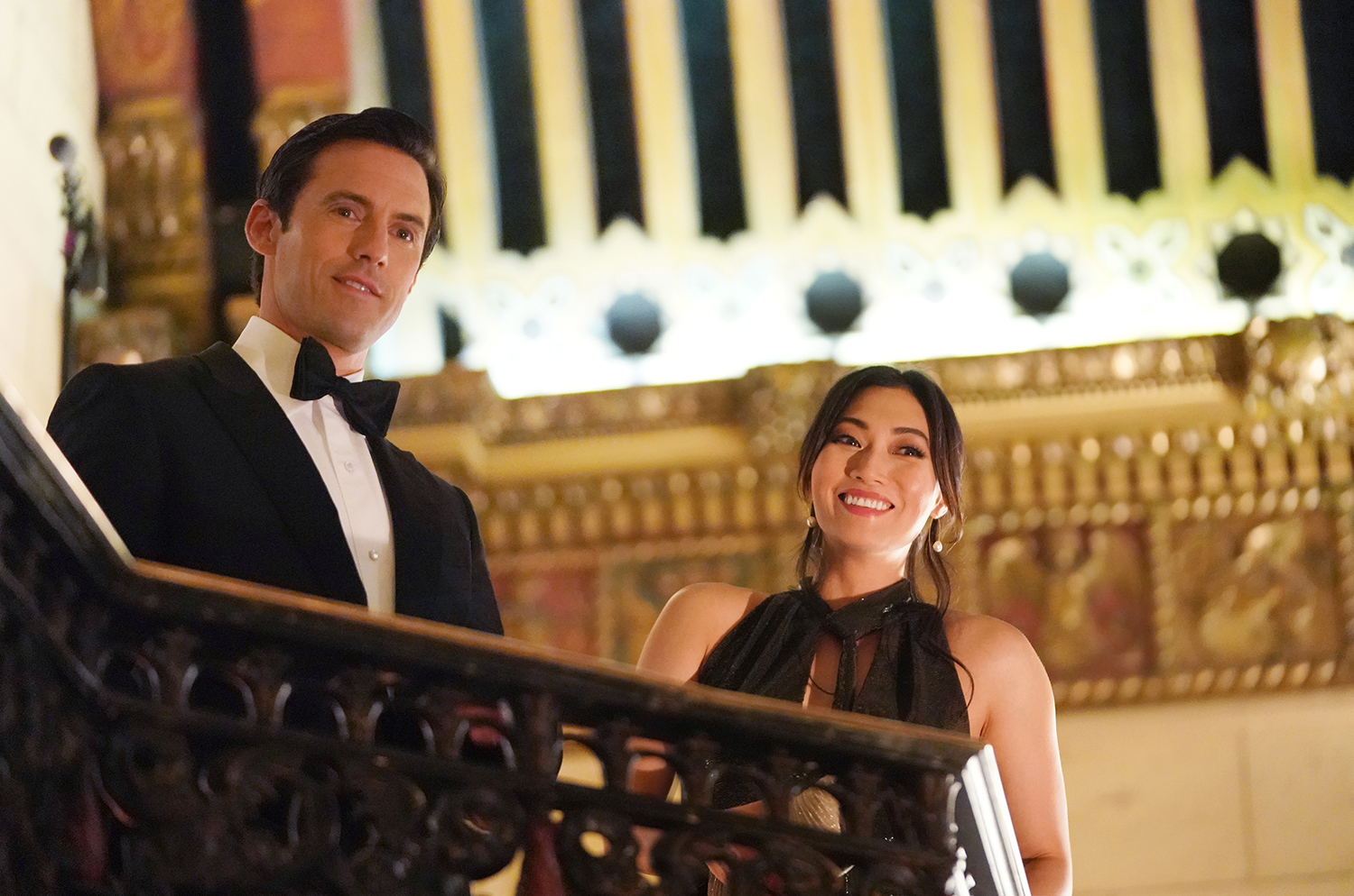 The Company You Keep stars Milo Ventimiglia and Catherine Haena Kim smile in formalwear on a staircase