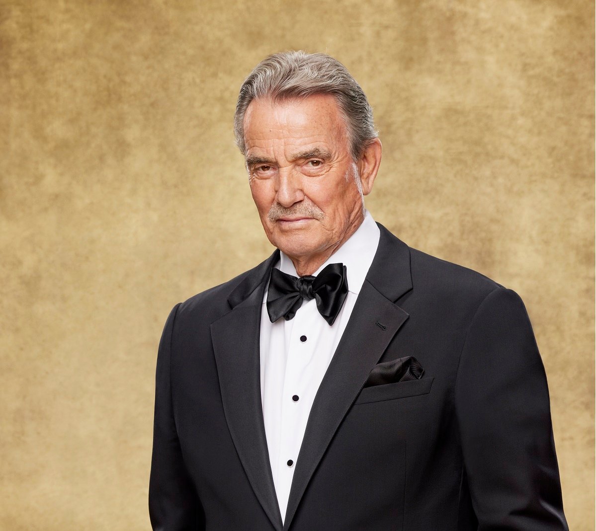 'The Young and the Restless' star Eric Braeden dressed in a tuxedo and posing in front of a gold backdrop.