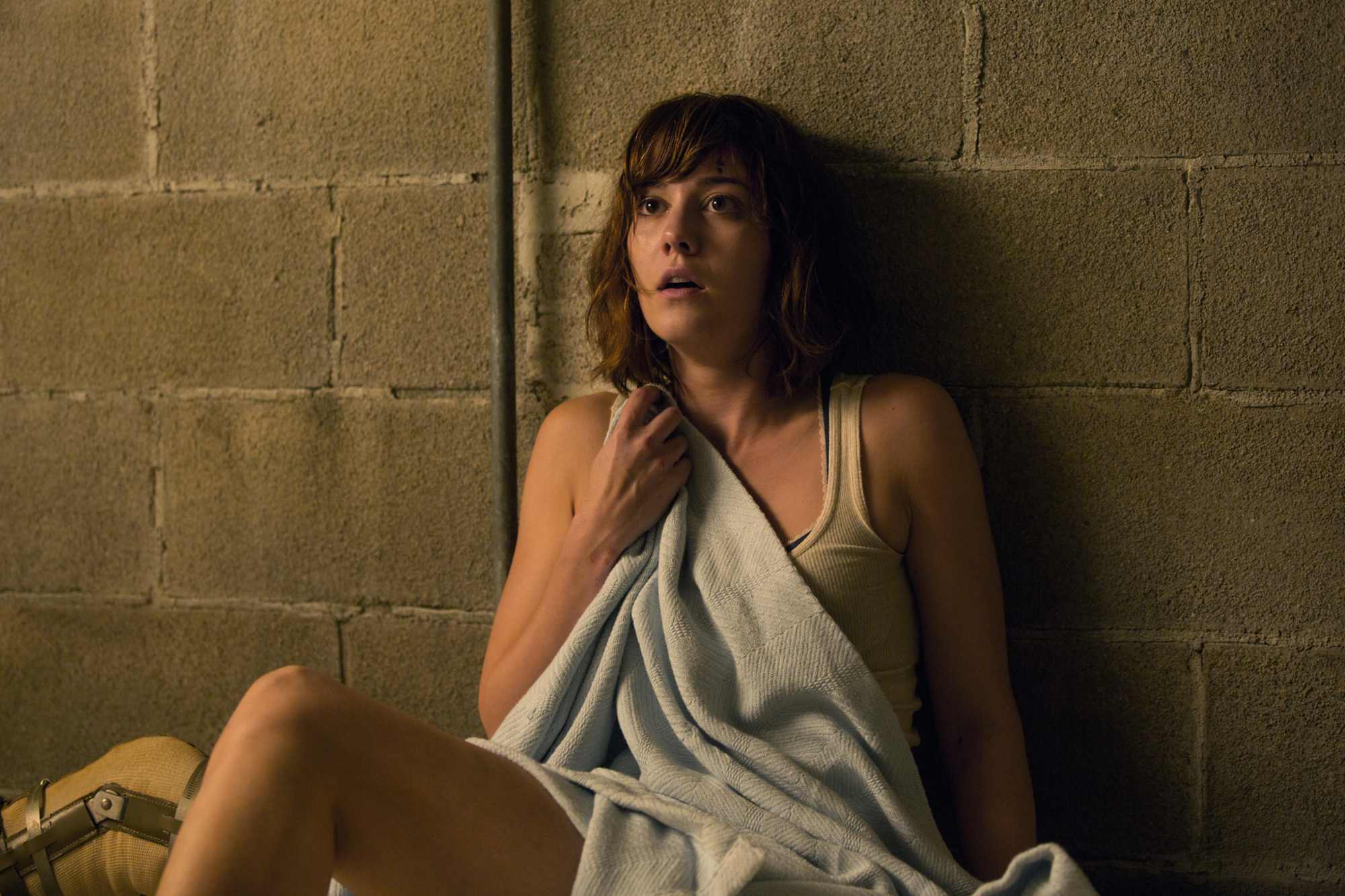 '10 Cloverfield Lane' Mary Elizabeth Winstead as Michelle looking terrified with her back against a wall, holding on to a blanket.