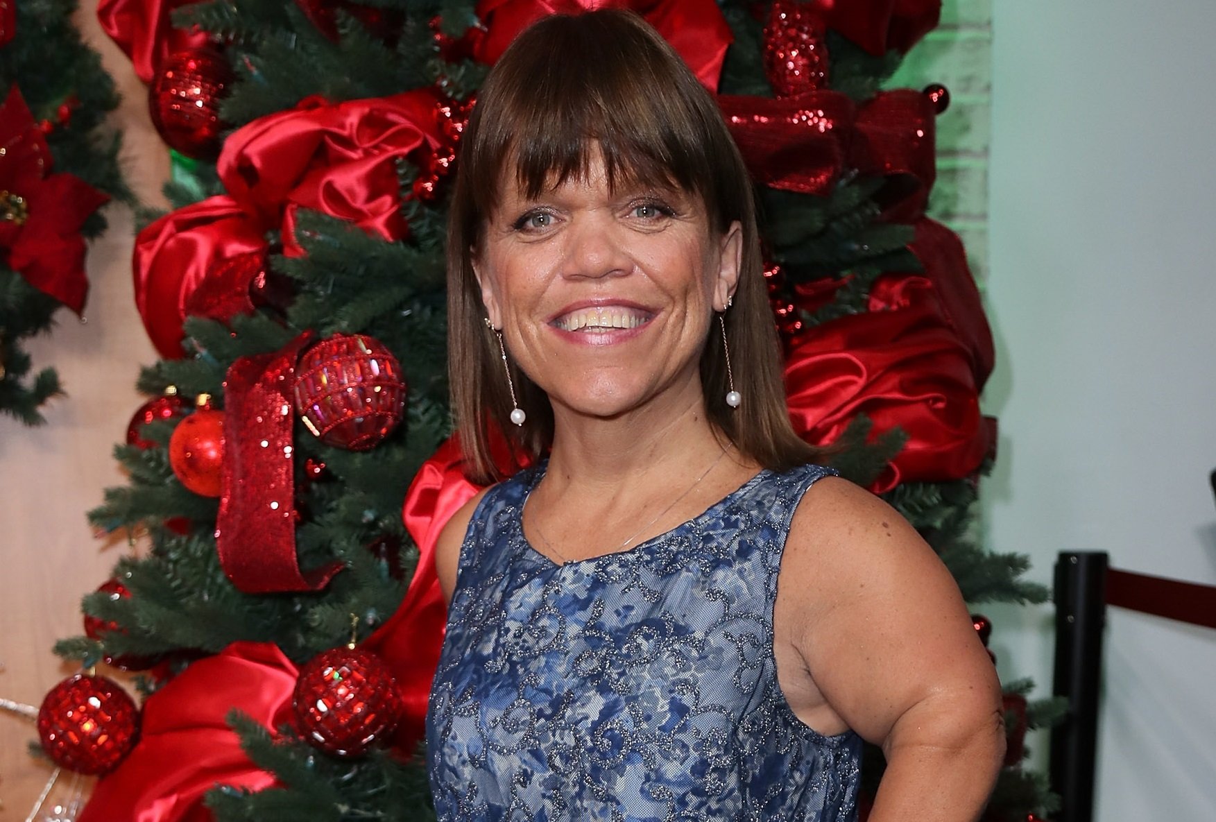 Amy Roloff smiles in front of a decorated Christmas tree