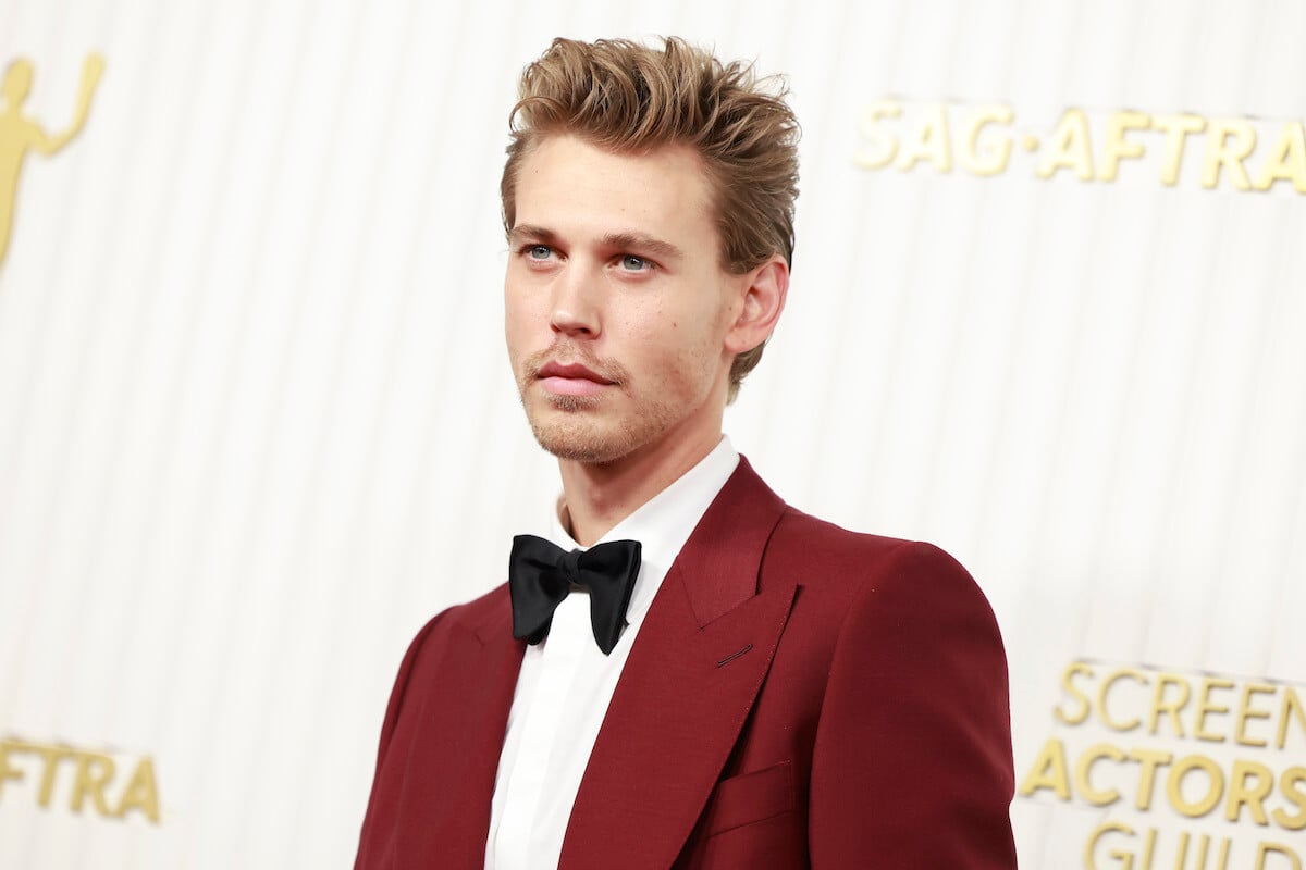 Austin Butler with a serious face wearing a red suit