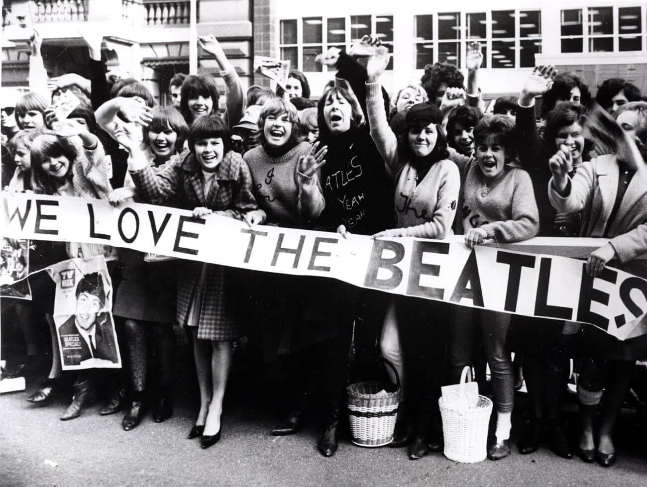 A black and white picture of Beatles fans holding a sign that says 