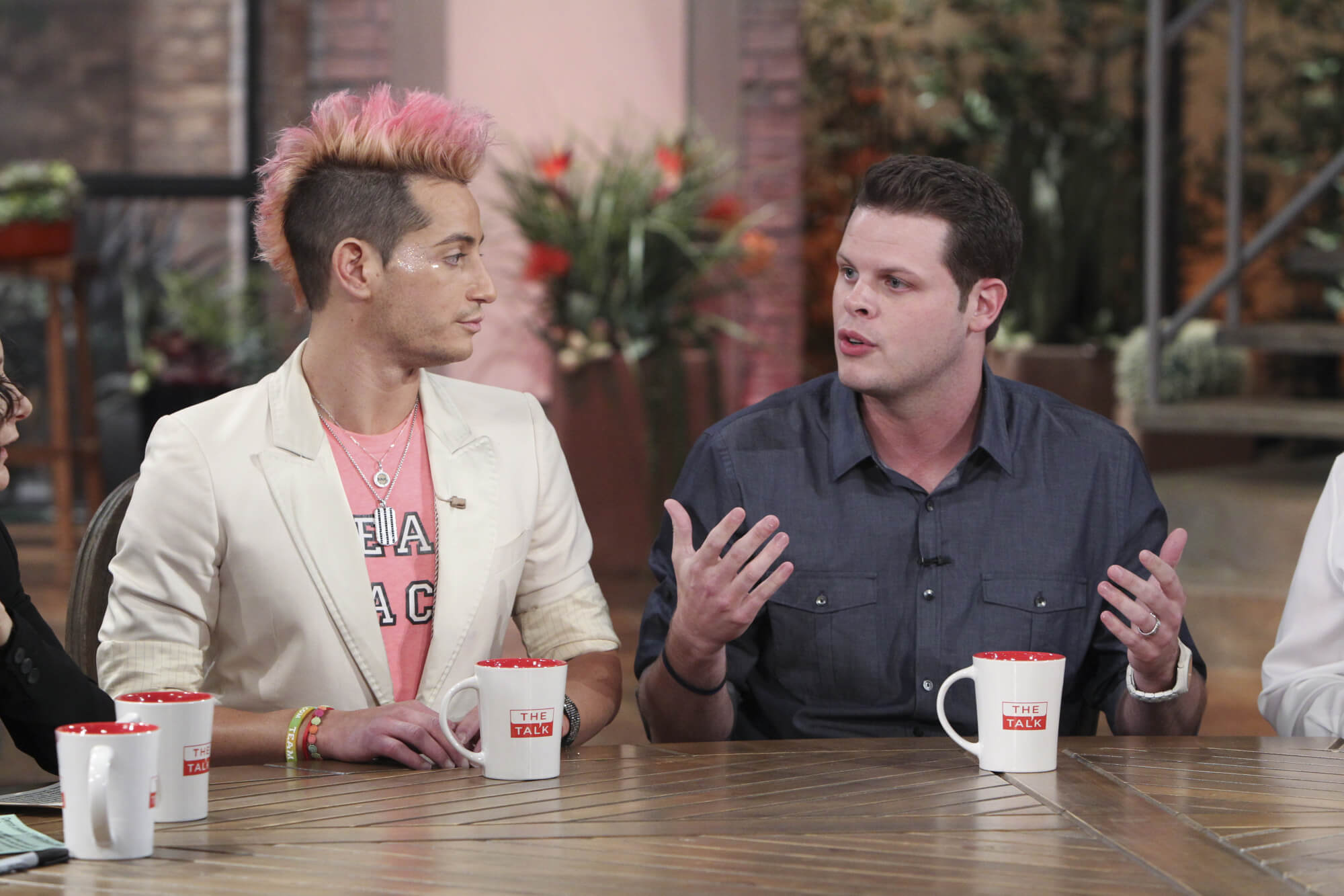 'Big Brother 16' houseguests Frankie Grande, who said he wanted to play again in 2023, and Derrick Levasseur visit 'The Talk.' Frankie wears a white suit over a pink shirt. Derrick wears a dark gray button-up shirt.