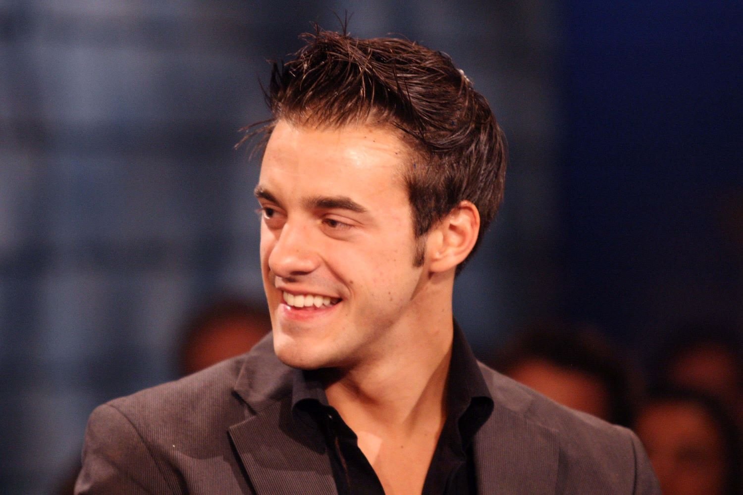 Gan Gheesling, the winner of 'Big Brother 10,' wears a dark gray suit over a black button-up shirt.