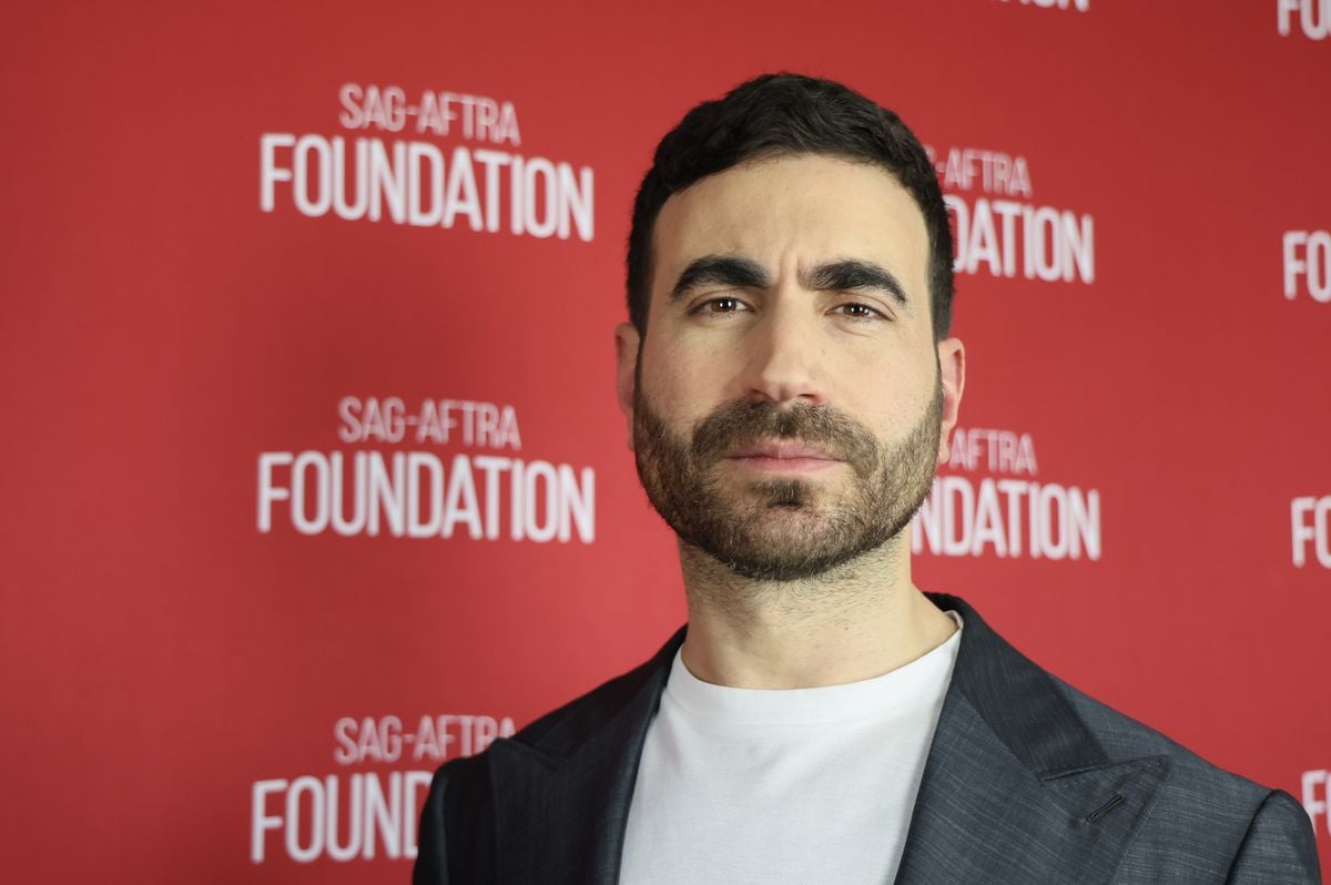 Brett Goldstein poses in front of a red backdrop featuring the SAG-AFTRA foundation logo.