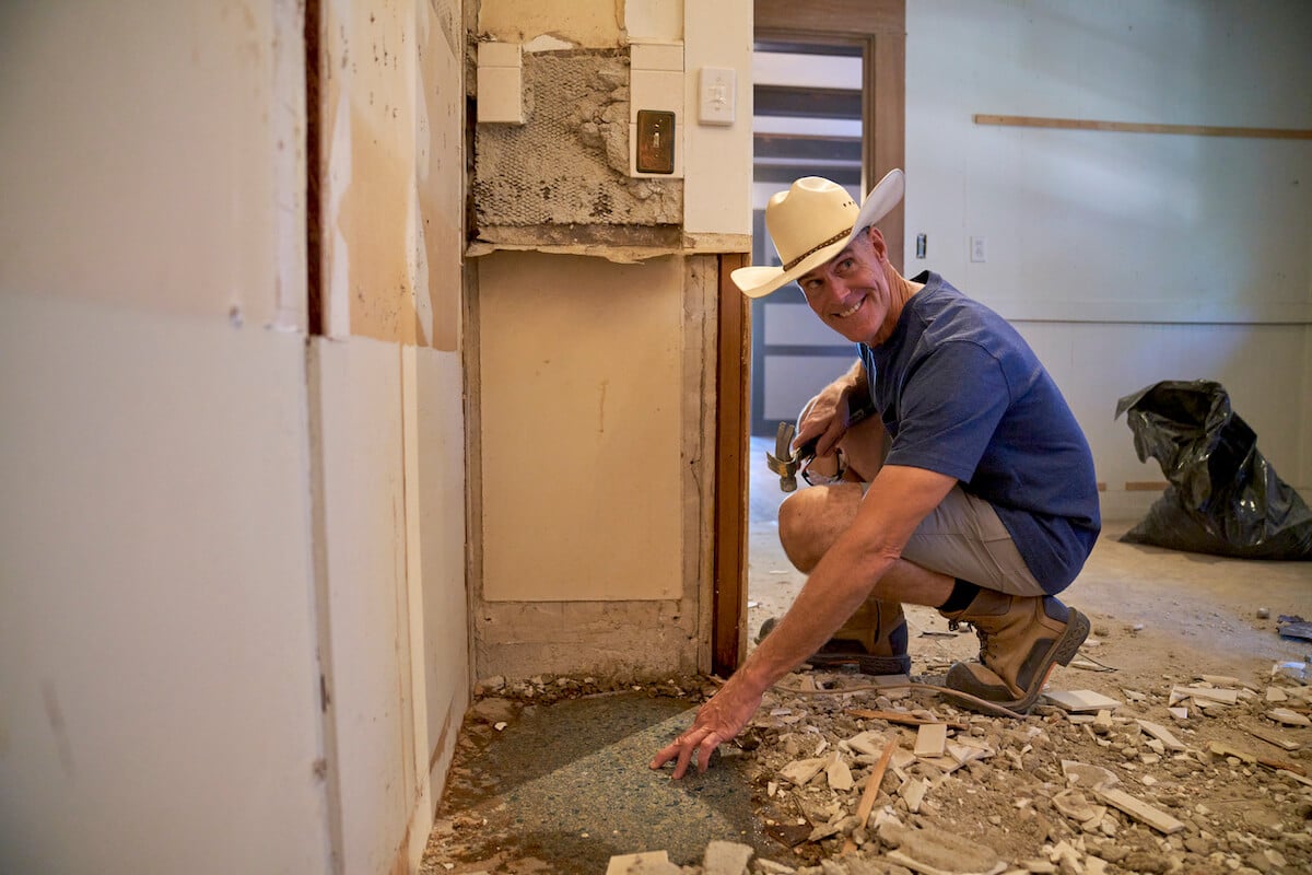 Brett Waterman crouching during a home renovation in an episode of 'Restored' on Magnolia Network