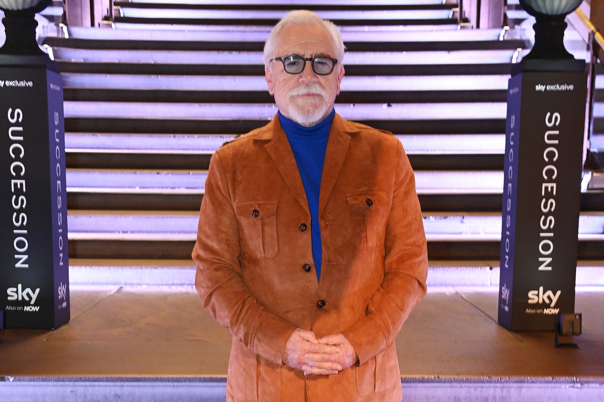 Brian Cox poses for a photo in front of lighted steps.