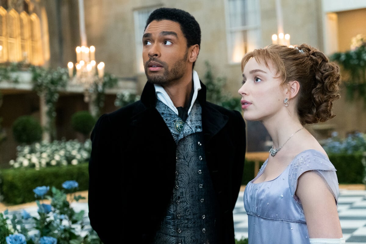 Regé-Jean Page as Simon Bassett and Phoebe Dynevor as Daphne Bridgerton looking off to the distance at their ball in 'Bridgerton'