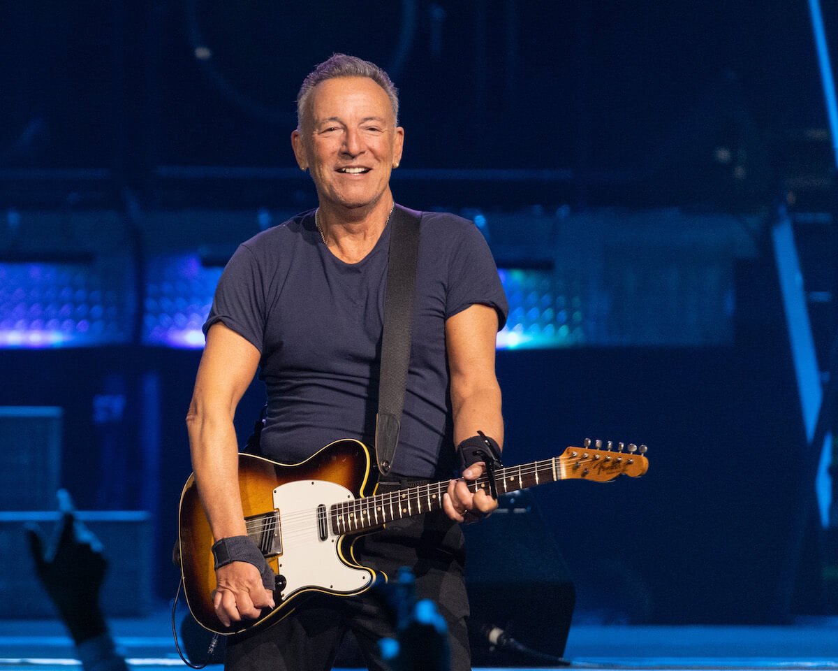 Bruce Springsteen holing a guitar performing on stage