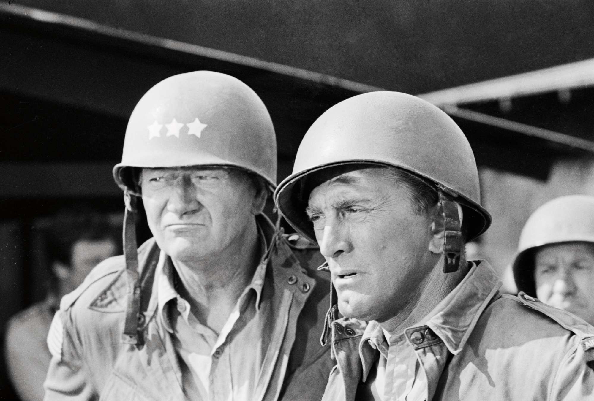 'Cast a Giant Shadow' John Wayne as U.S. General Randolph and Kirk Douglas, as Kirk Douglas, as U.S. Colonel David Marcus in a black-and-white picture. They're wearing military uniforms, looking upset.