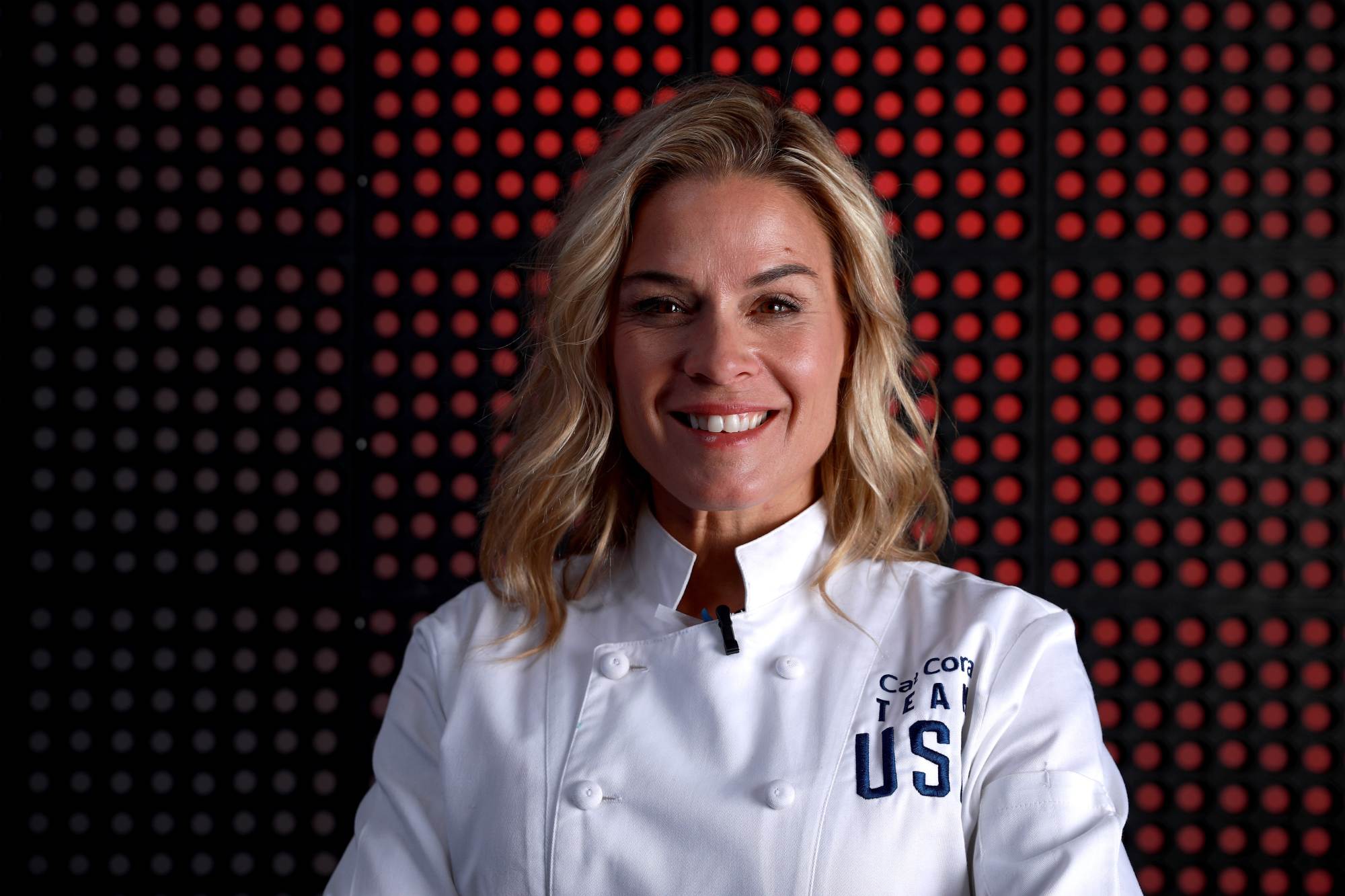 Cat Cora wearing a chef's jacket, smiling in a portrait.