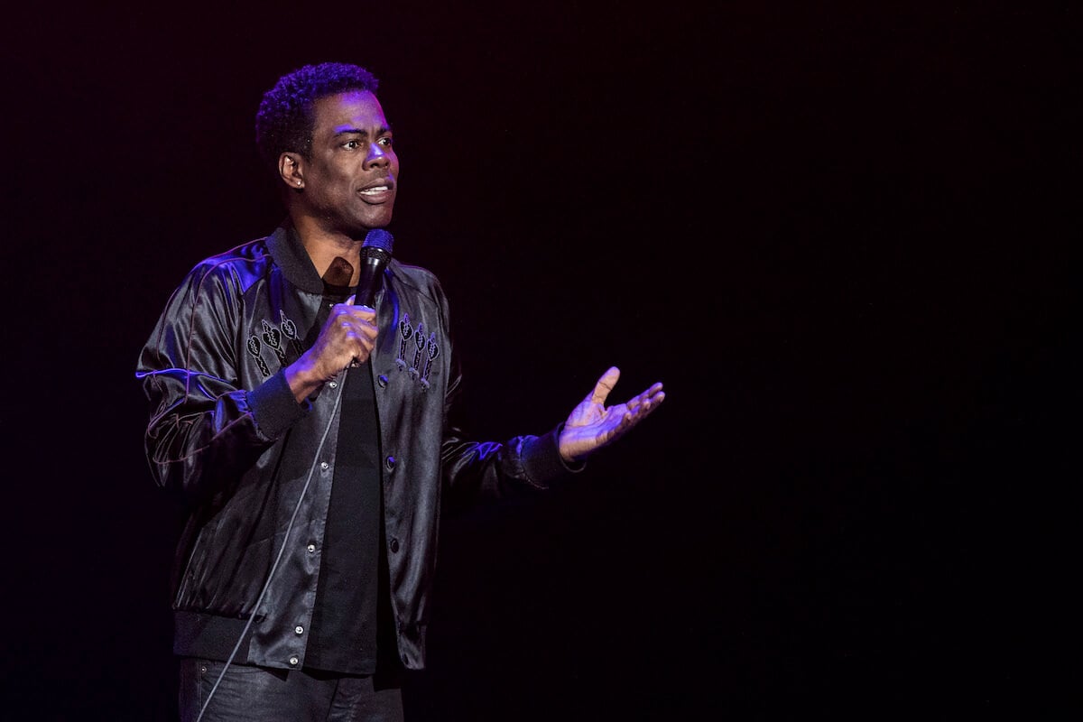 Chris Rock holding a microphone performing standup
