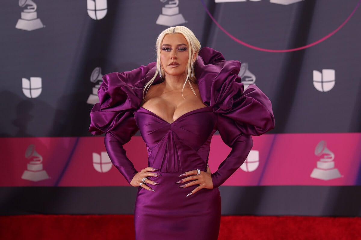 Christina Aguilera posing on the red carpet wearing purple with her hands on her hips