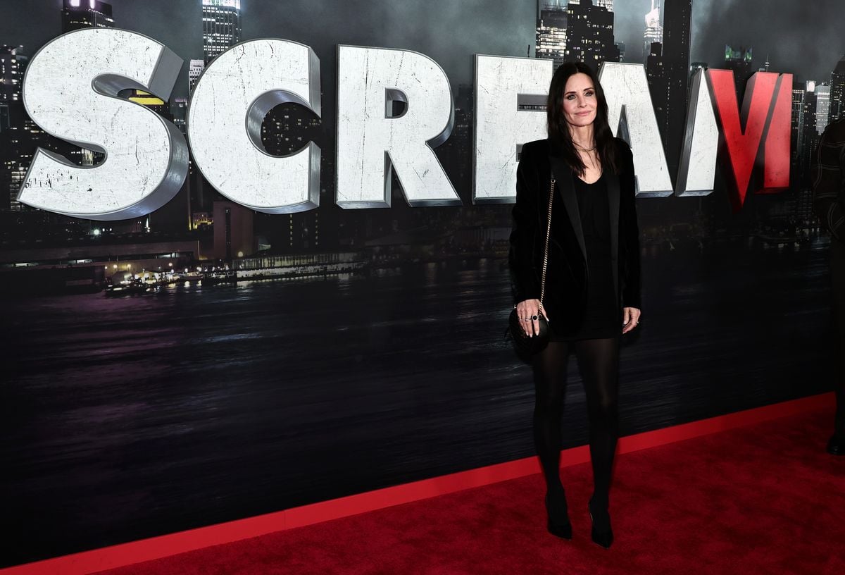Courteney Cox poses for photos in front os a backdrop featuring the "Scream VI" logo.