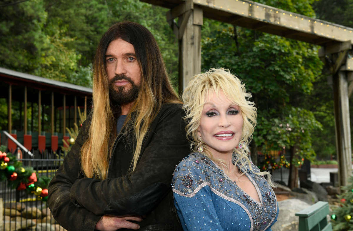 Billy Ray Cyrus and Dolly Parton pose together standing back-to-back.