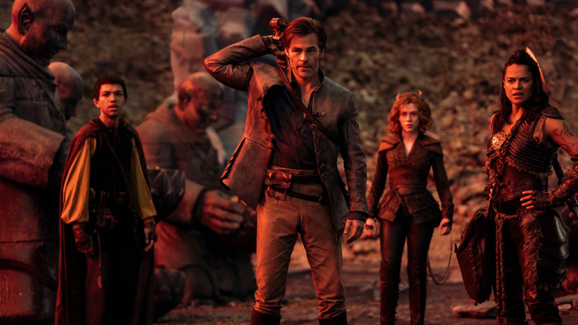 'Dungeons & Dragons: Honor Among Thieves' Justice Smith as Simon, Chris Pine as Edgin, Sophia Lillis as Doric, and Michelle Rodriguez as Holga standing in front of statues looking worried.